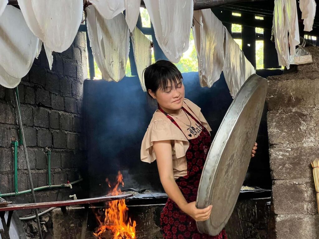 A woman prepares trays of noodles (pho).